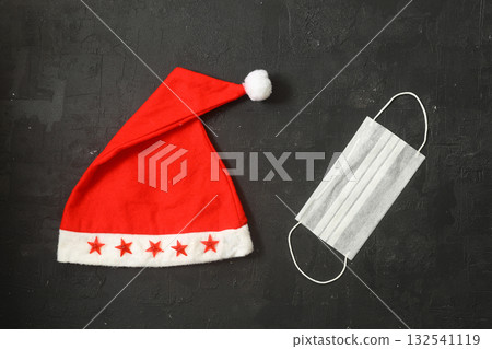 Funny christmas greeting card with santa hat and medical face mask. Flat lay with copy space Funny christmas greeting card with santa hat and medical face mask. Flat lay with copy space 132541119
