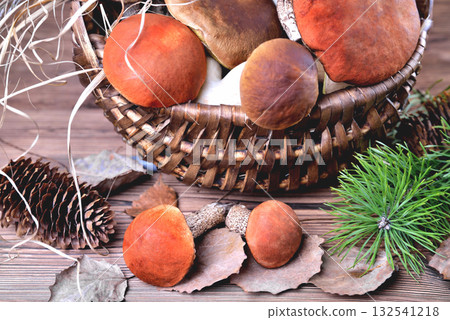 Edible mushrooms, porcini and boletus in a wicker basket on a natural wooden background 132541218