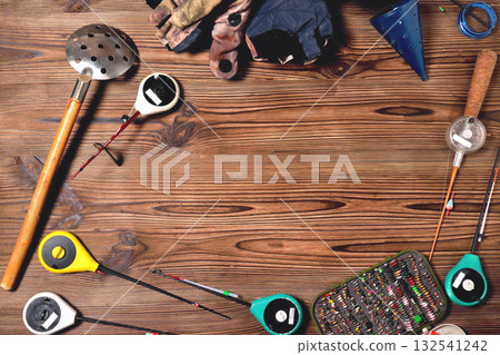 accessories for winter fishing on a brown wooden background, place for an inscription 132541242