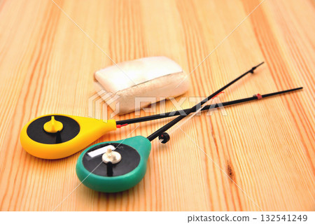 Equipped with fishing rods for winter fishing and a box for bait on a natural wooden background, close-up, place for inscription 132541249