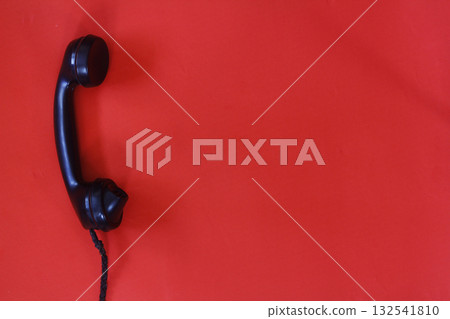 black old telephone receiver hanging on red background with texting space, waiting for phone call, vintage telephone. 132541810