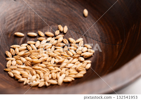 Raw cat grass grains on wooden bowl texture close up Raw cat grass grains on wooden bowl texture close up 132541953