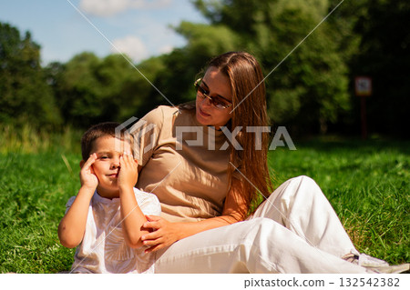 Mother with kid having fun in public green park. Happy mom laughing together with son. Quality leisure time outside. Mother with kid having fun in public green park. Happy mom laughing together with son. Quality leisure time outside. 132542382