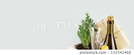 Christmas or New Year, holiday banner with Small Christmas tree in a pot, bottle of champaign, glasses and gift on a blue background with copy space. Zero waste eco Christmas and New Year concept 132542468