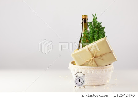 Christmas or New Year, holiday card with Small, home planted Christmas tree, bottle of champaign, candle, gift and clock on a white table with copy space. Zero waste eco Christmas and New Year concept Christmas or New Year, holiday card with Small, home planted Christmas tree, bottle of champaign, candle, gift and clock on a white table with copy space. Zero waste eco Christmas and New Year concept 132542470