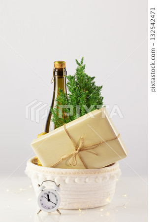 Christmas or New Year, holiday card with Small, home planted Christmas tree, bottle of champaign, candle, gift and clock on a white table. Zero waste eco Christmas and New Year concept Christmas or New Year, holiday card with Small, home planted Christmas tree, bottle of champaign, candle, gift and clock on a white table. Zero waste eco Christmas and New Year concept 132542471