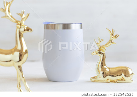 Blank Stainless Steel wine tumbler near golden Christmas deers on white table closeup, mockup Blank Stainless Steel wine tumbler near golden Christmas deers on white table closeup, mockup 132542525