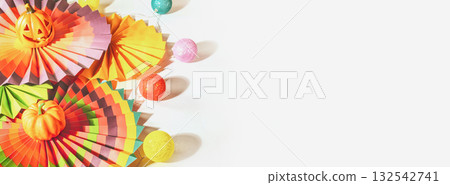 Halloween banner with colorful paper fans, decorative pumpkin, lightening and jack o'lantern on a white background with place for your text. Mexican, Halloween background. Soft focus, Banner size 132542741