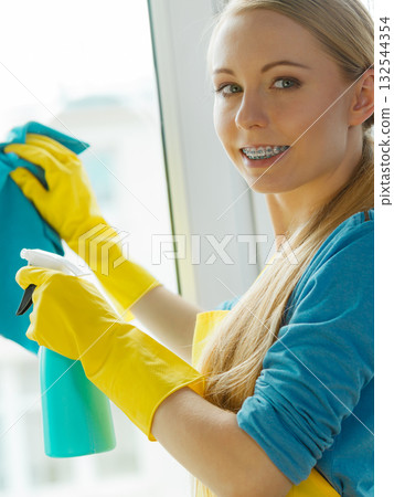 Girl cleaning window at home using detergent rag 132544354