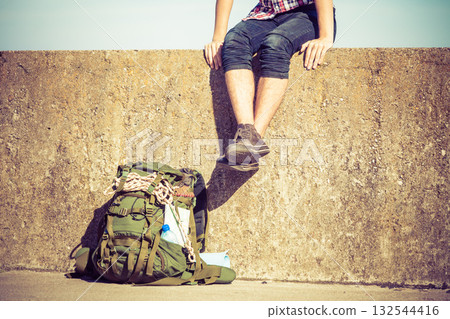 Man tourist backpacker sitting on grunge wall outdoor 132544416
