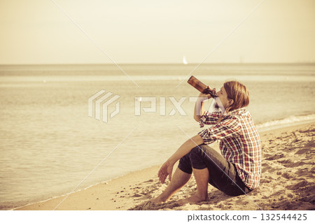Man depressed with wine bottle sitting on beach outdoor Man depressed with wine bottle sitting on beach outdoor 132544425