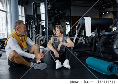 Mature couple are having a conversation while resting in a gym 132544744