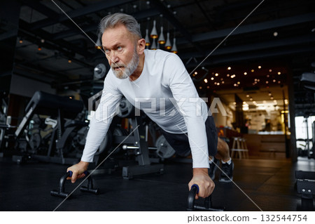 Mature man is doing push-ups in a modern gym 132544754