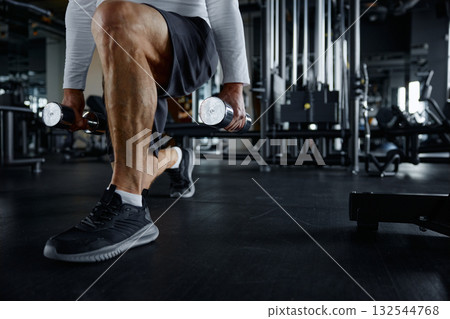 Eldery man and a woman squatting with dumbbells inside a gym Eldery man and a woman squatting with dumbbells inside a gym 132544768