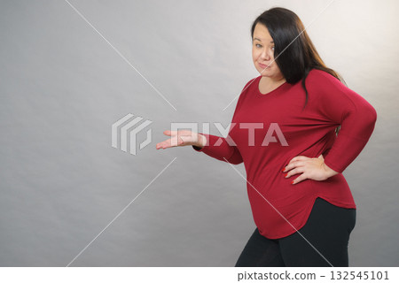 Woman in red pointing with doubt 132545101