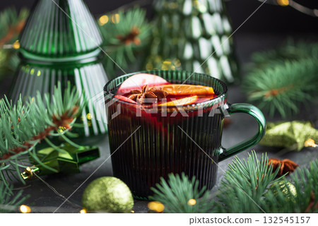 Holiday Mulled Wine with Orange and Apple in Green Mug Surrounded by Christmas Decor Holiday Mulled Wine with Orange and Apple in Green Mug Surrounded by Christmas Decor 132545157