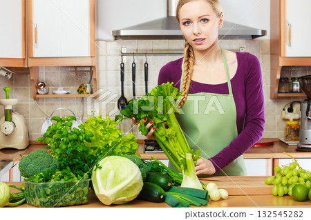Woman in kitchen with green vegetables 132545282