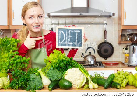 Woman in kitchen having green diet vegetables Woman in kitchen having green diet vegetables 132545290