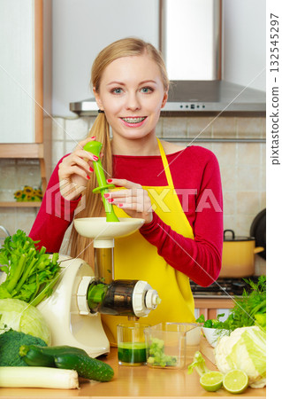 Woman in kitchen making vegetable smoothie juice 132545297
