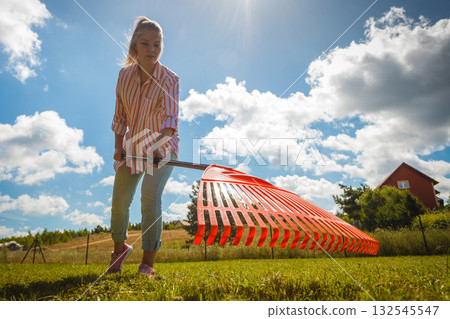 Unusual angle of woman raking leaves Unusual angle of woman raking leaves 132545547