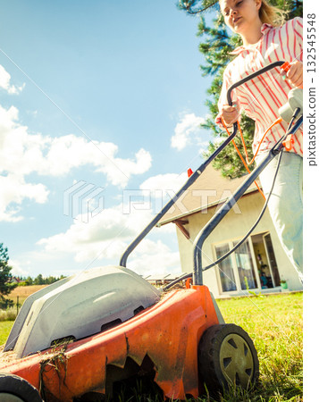 Woman mowing green grass Woman mowing green grass 132545548