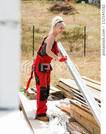 Woman carrying gutter on construction site Woman carrying gutter on construction site 132545582
