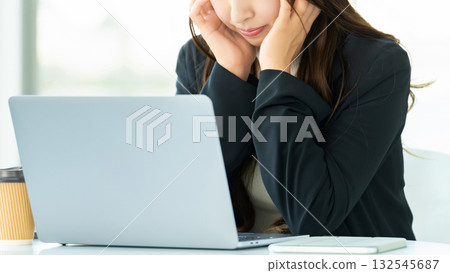 A woman worried while using a computer A woman worried while using a computer 132545687