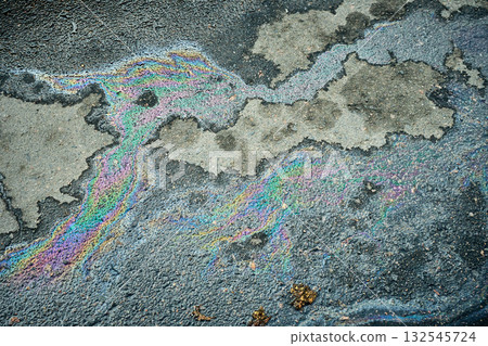 Multicolored gasoline slick crafting beautiful iridescent patterns on the damp pavement. 132545724