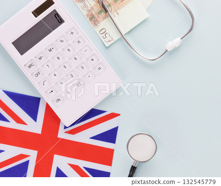 Medical insurance in Great Britain. Calculator, stethoscope, flag of Great Britain and pounds on a blue background. Treatment and medical care in the UK 132545779