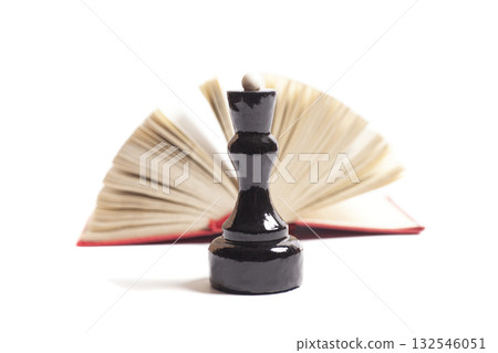 The queen's chess piece in front of an open book 132546051