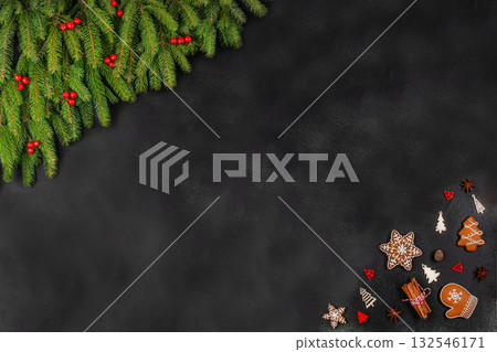 Christmas background with fir branches, red berries, gingerbread cookies and wooden decorations on dark surface, festive flat lay with copy space for text 132546171