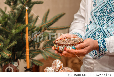 Traditional Ukrainian kutia served on Christmas Eve in ceramic bowl with embroidered shirt, festive ritual dish with wheat and poppy seeds, kutia for Holy Supper in authentic ethnic setting 132546175