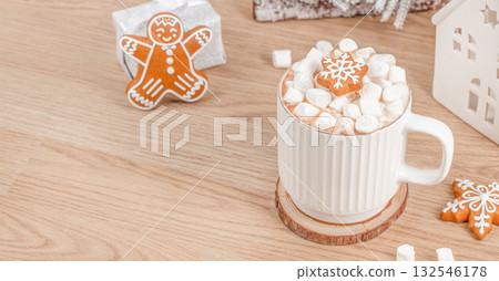 White mug of hot chocolate with marshmallows and snowflake gingerbread cookie on wooden table, festive winter drink with Christmas decor and gift box in cozy holiday atmosphere, copy space White mug of hot chocolate with marshmallows and snowflake gingerbread cookie on wooden table, festive winter drink with Christmas decor and gift box in cozy holiday atmosphere, copy space 132546178