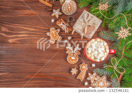 Christmas flat lay with cup of cocoa and marshmallows, gingerbread cookies, gift box, fir branches and cinnamon sticks on wooden table, festive holiday composition with copy space for text 132546181