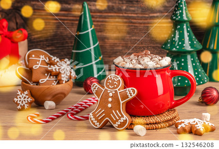 Warm Christmas spirit concept with red mug of hot chocolate, marshmallows, and gingerbread cookies symbolizing coziness, joy, and festive comfort Warm Christmas spirit concept with red mug of hot chocolate, marshmallows, and gingerbread cookies symbolizing coziness, joy, and festive comfort 132546208
