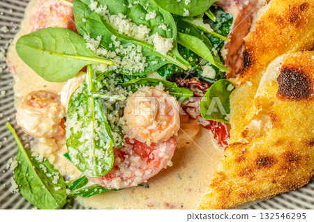 Creamy shrimp dish with spinach, sun-dried tomatoes, and parmesan served with crispy focaccia bread Creamy shrimp dish with spinach, sun-dried tomatoes, and parmesan served with crispy focaccia bread 132546295