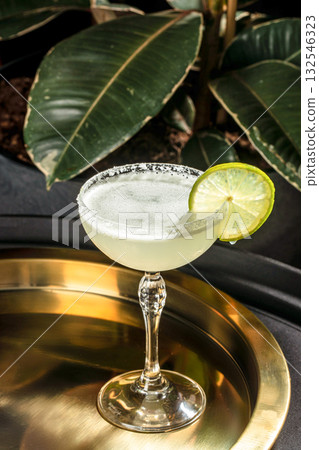 Refreshing margarita cocktail with lime garnish and salted rim served in an elegant glass on a golden tray Refreshing margarita cocktail with lime garnish and salted rim served in an elegant glass on a golden tray 132546323