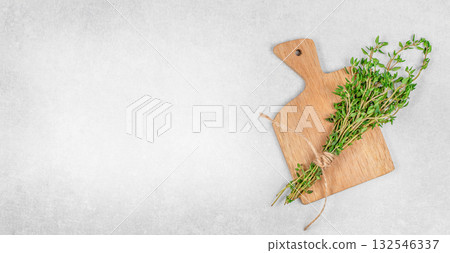 Fresh thyme bunch tied with rope on wooden cutting board over gray stone background with copy space. Organic herbs for cooking, natural seasoning, food template design Fresh thyme bunch tied with rope on wooden cutting board over gray stone background with copy space. Organic herbs for cooking, natural seasoning, food template design 132546337