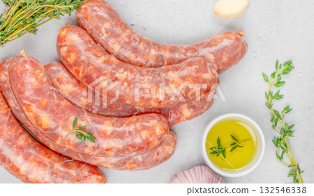 Raw pork sausages with spices, garlic, thyme, and olive oil on light background. Fresh homemade sausage, uncooked meat, organic food ingredient for barbecue and grill 132546338