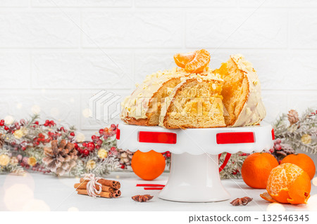 Traditional Christmas panettone cake with white chocolate glaze and mandarin on festive background, holiday dessert on cake stand with winter decorations and copy space Traditional Christmas panettone cake with white chocolate glaze and mandarin on festive background, holiday dessert on cake stand with winter decorations and copy space 132546345
