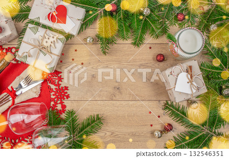 Christmas background with fir branches, gifts, candle, cutlery, wine glasses and festive decorations on wooden table, copy space for text, holiday celebration concept Christmas background with fir branches, gifts, candle, cutlery, wine glasses and festive decorations on wooden table, copy space for text, holiday celebration concept 132546351