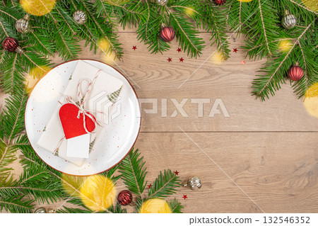 Christmas gift box on a plate with festive fir branches, baubles and free copy space top view Christmas gift box on a plate with festive fir branches, baubles and free copy space top view 132546352