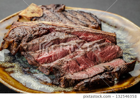 Close up of juicy grilled beef steak T-bone sliced medium rare and served on a ceramic plate. Perfect gourmet meat dish for steakhouse, barbecue, restaurant menu, or culinary advertising Close up of juicy grilled beef steak T-bone sliced medium rare and served on a ceramic plate. Perfect gourmet meat dish for steakhouse, barbecue, restaurant menu, or culinary advertising 132546358