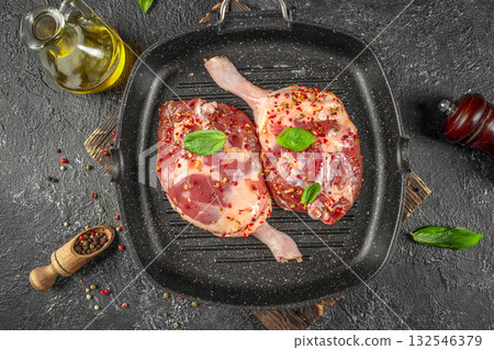 Raw duck legs seasoned with herbs and pepper in a grill pan, ready for traditional confit preparation. top view Raw duck legs seasoned with herbs and pepper in a grill pan, ready for traditional confit preparation. top view 132546379