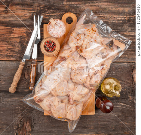 Vacuum sealed package of fresh raw quail meat with spices, prepared for retail sale on rustic wooden table. Vacuum sealed package of fresh raw quail meat with spices, prepared for retail sale on rustic wooden table. 132546410