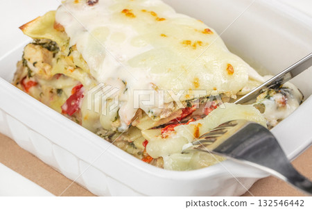 Delicious baked lasagna with layers of pasta, meat sauce, and creamy melted cheese served in a container Delicious baked lasagna with layers of pasta, meat sauce, and creamy melted cheese served in a container 132546442