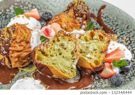 Profiteroles with pistachio cream and chocolate served with fresh berries Profiteroles with pistachio cream and chocolate served with fresh berries 132546444