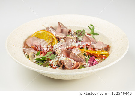 Close-up of a gourmet salad with slices of roast beef, fresh vegetables, and orange garnish served in a bowl 132546446