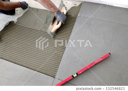 Worker hands putting ceramic tiles on the floorl. Worker hands putting ceramic tiles on the floorl. 132546821