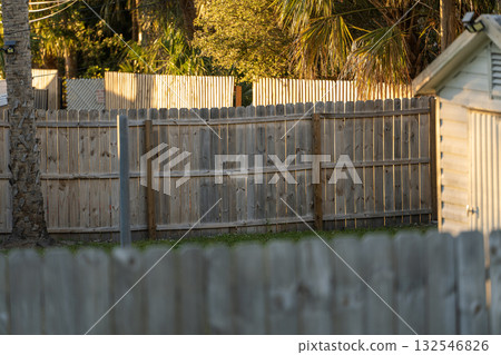 Wooden plank fence in Florida backyard. Timber fencing for grounds protection and privacy Wooden plank fence in Florida backyard. Timber fencing for grounds protection and privacy 132546826